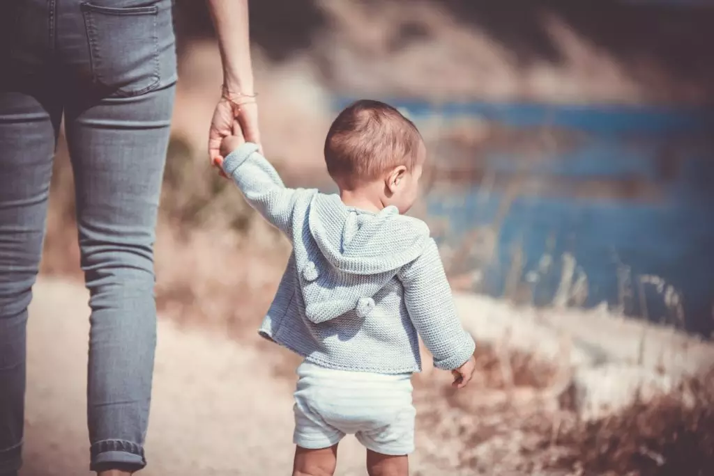 mãe de mãos dadas com criança pequena em guarda provisória