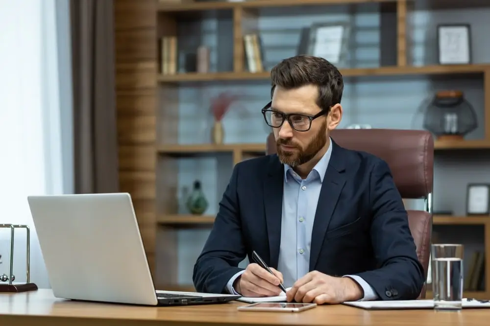 Homem de terno sentado em frente a notebook