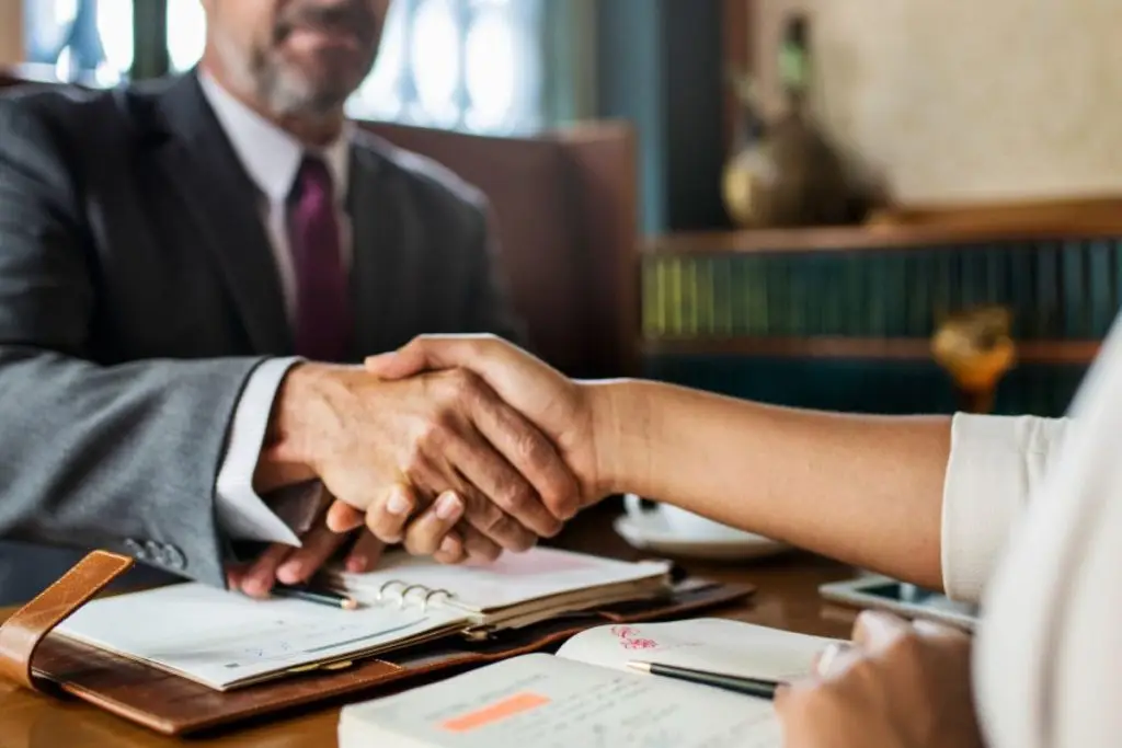 Advogado apertando a mão de uma cliente, representando como captar clientes na advocacia.