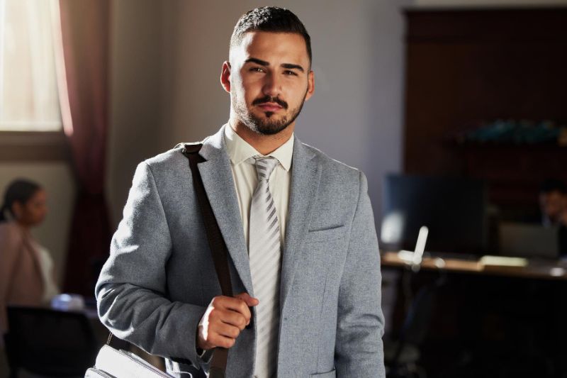 Advogado em pé com uma bolsa lateral.