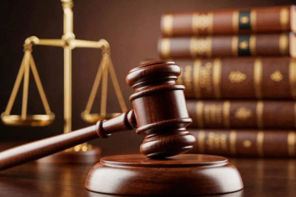 Malhete com balança de Têmis e livros ao fundo, representando as atividades incompatíveis com a advocacia.