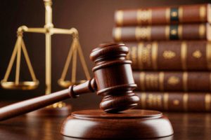 Malhete com balança de Têmis e livros ao fundo, representando as atividades incompatíveis com a advocacia.