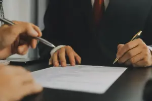 Mão masculina assinando um contrato de prestação de serviço jurídico.