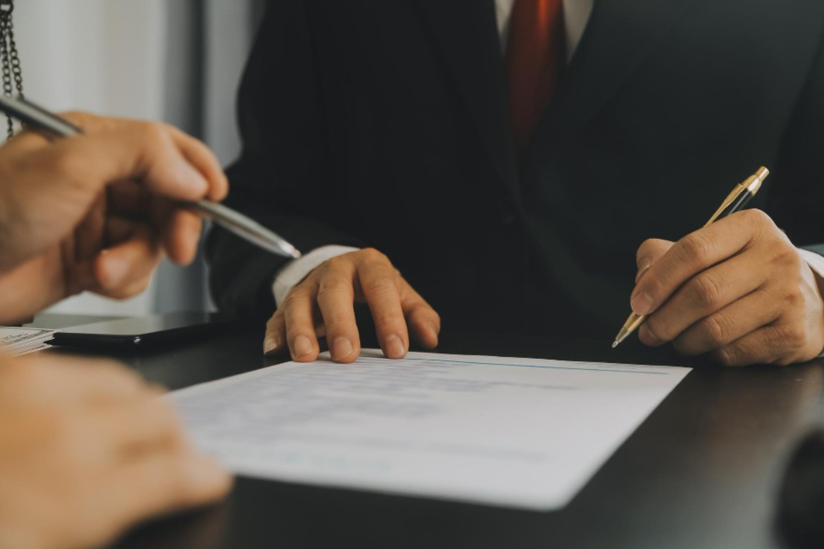Mão masculina assinando um contrato de prestação de serviço jurídico.
